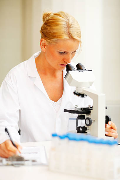 istock Attractive female researcher looking into a microscope 182880070