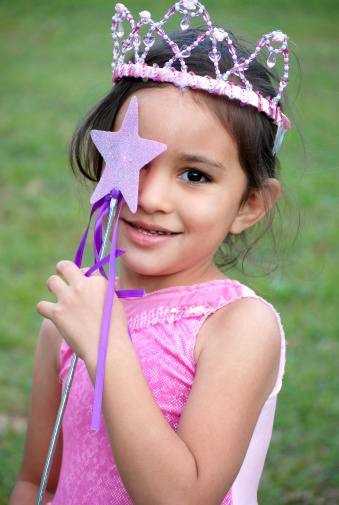 A pink princess holds up a star wand to cover an eye.