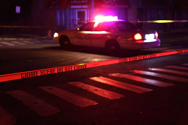 Crime Scene with Police Car Police car and crime scene tape on a city street crime stock pictures, royalty-free photos & images