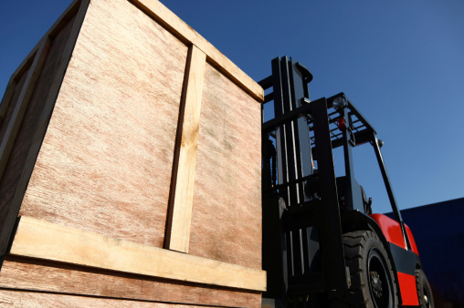 A  forklift loading a container onto the back of a truck.