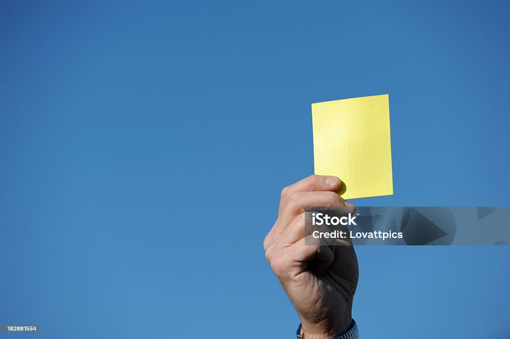 Yellow card. referee. A football referee holding up a yellow card against a blue sky. Yellow Card - Sport Symbol Stock Photo