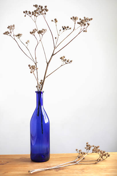 Arrengement of dried wild flowers in blue vase on a table.