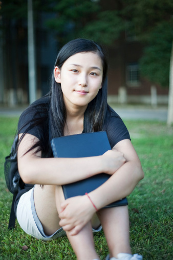 Young asian schoolgirl sitting on grass.