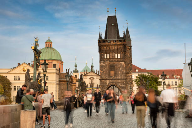 Prague, Czechia - September 13, 2022:  People walk by the artists and historic sculptures across the Charles bridge over the Vlatava River in Czech Republic Czechia Europe