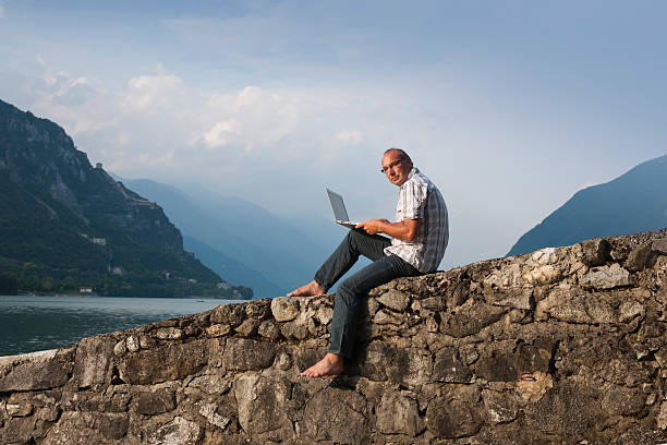 istock Man with laptop sitting on wall 182882671