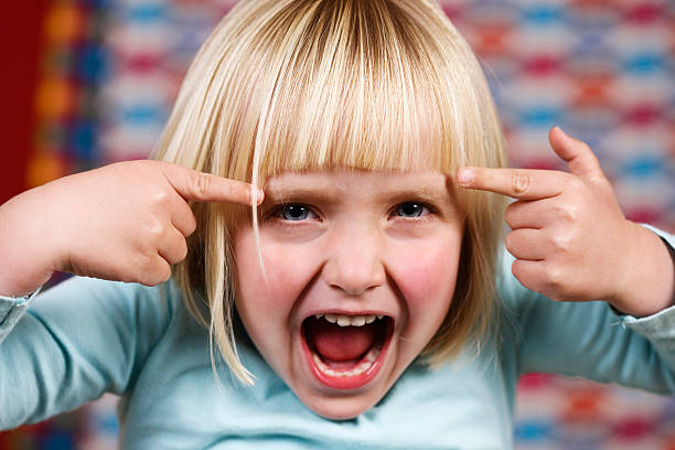 piccola ragazza bionda punti per la sua testa, gridare - impatient children only child anger foto e immagini stock