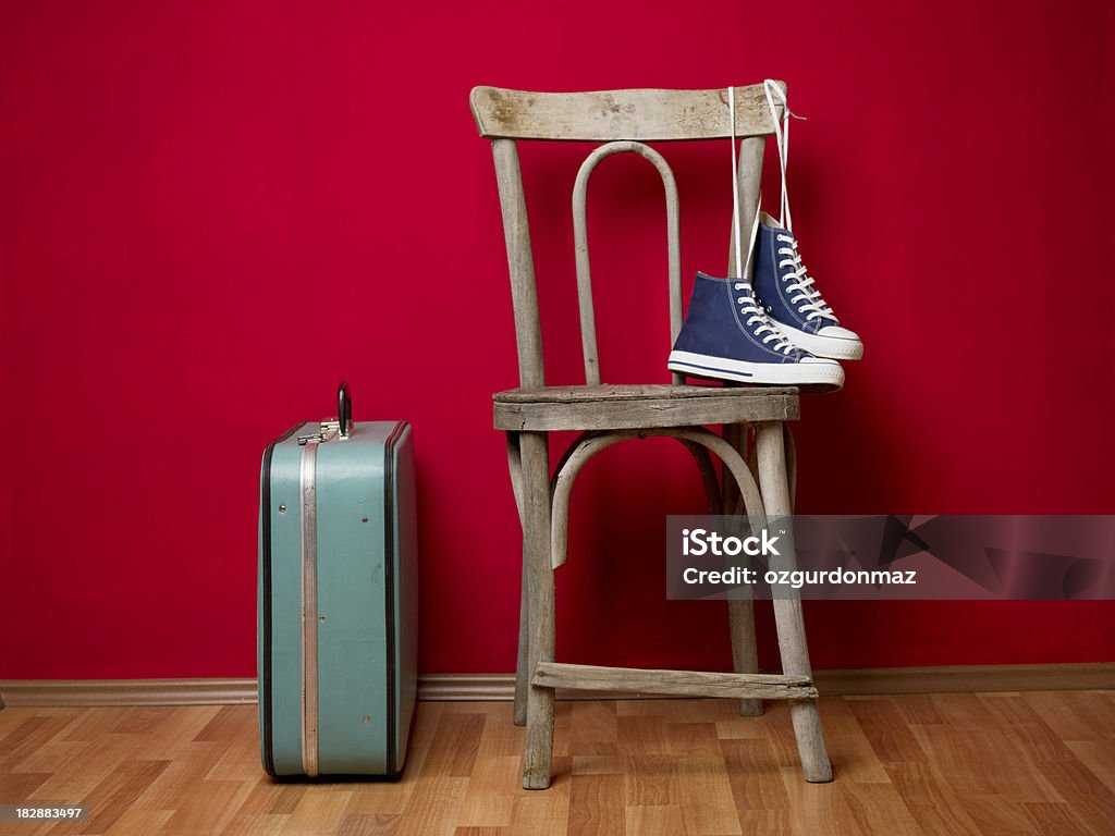 Moving house "Old fashioned suitcase, pair of canvas shoes and old chair in the empty room" Antique Stock Photo