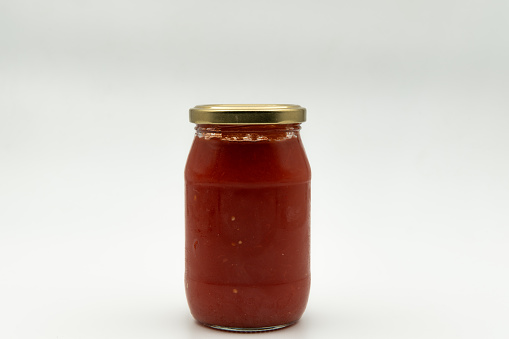 Tomato sauce in a glass jar on a white background