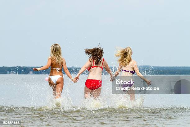 Vista Traseira De Três Mulheres Jovens A Correr Em Água Lakeside - Fotografias de stock e mais imagens de Adulto