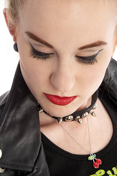 Woman with blonde hair red lipstick and studded collar Young blonde woman in studded collar and black leather jacket looking down. Vertical studio shot on white. Tied Up Bondage Women Fetish Wear stock pictures, royalty-free photos & images