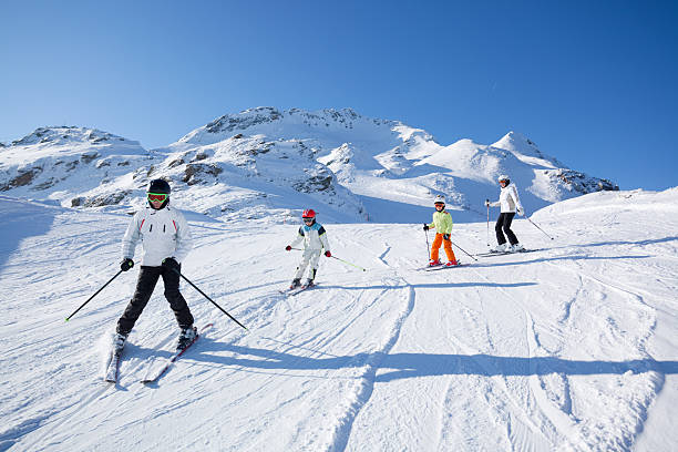istock family skiing on sunny day 182885496