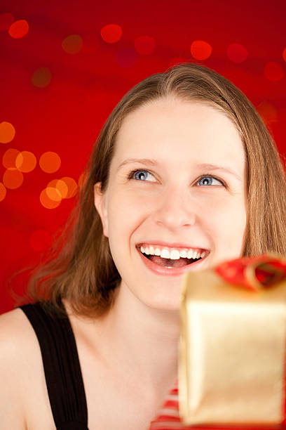 istock Young Woman Looking Up While Holding Wrapped Presents 182886661