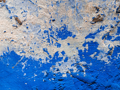 Abstract blue paint grunge background. Weathered scratched cement wall with flaking and peeling paint. Abstract rough wallpaper with copy space.