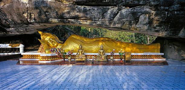 leżący budda tajski obraz pod rock arch, tajlandia. - reclining buddha zdjęcia i obrazy z banku zdjęć