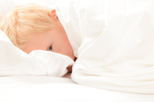young blond boy in bed but not really sleeping.Check out our other shots of children!