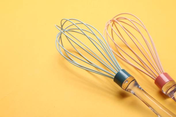 istock Two whisks on yellow background, closeup. Space for text 1828892685