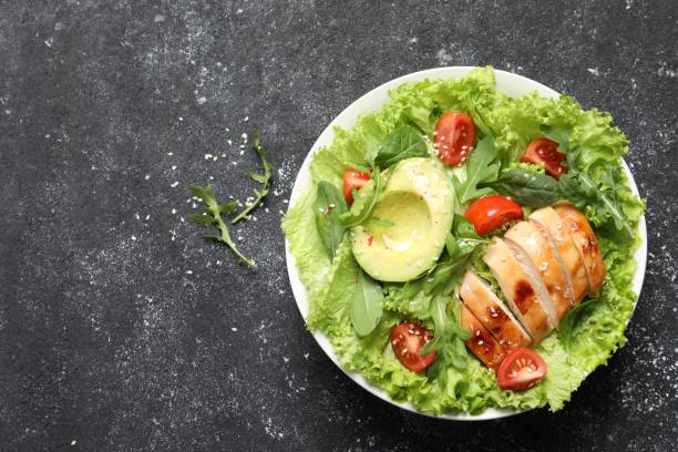 istock Delicious salad with chicken, cherry tomato and avocado on grey textured table, top view. Space for text 1828893260
