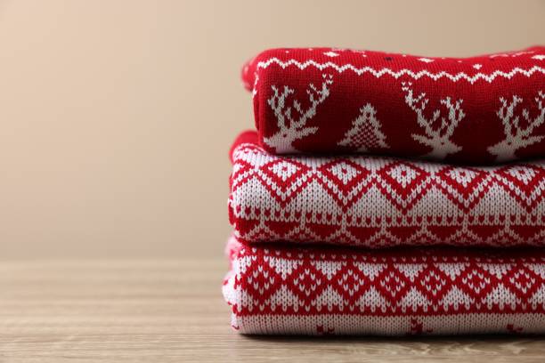 istock Stack of different Christmas sweaters on wooden table against beige background, closeup. Space for text 1828897452