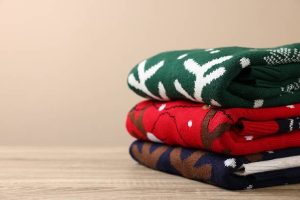 istock Stack of different Christmas sweaters on wooden table against beige background, closeup. Space for text 1828897461