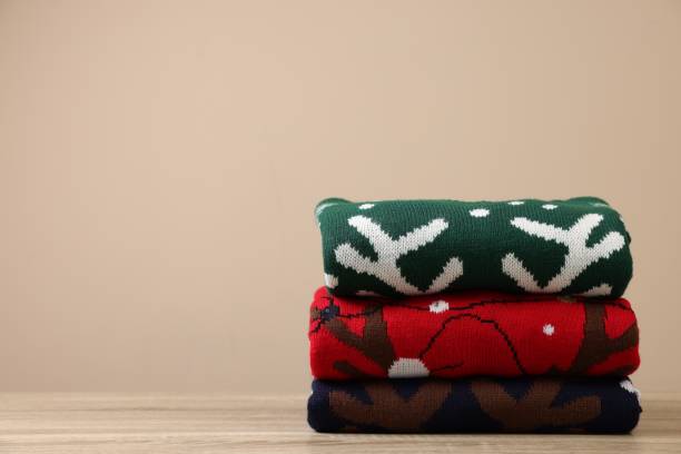 istock Stack of different Christmas sweaters on wooden table against beige background, space for text 1828897462
