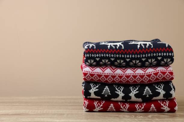 istock Stack of different Christmas sweaters on wooden table against beige background, space for text 1828897468
