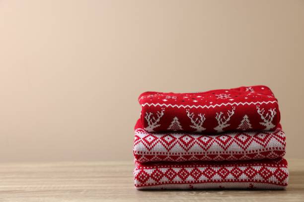 istock Stack of different Christmas sweaters on wooden table against beige background, space for text 1828899653