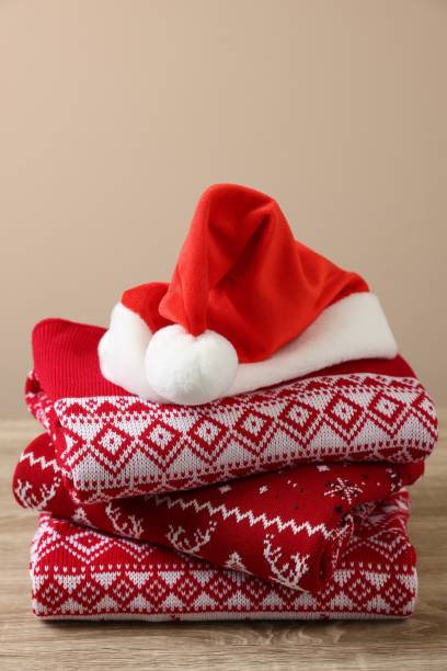 istock Stack of different Christmas sweaters and Santa hat on wooden table against beige background 1828900216