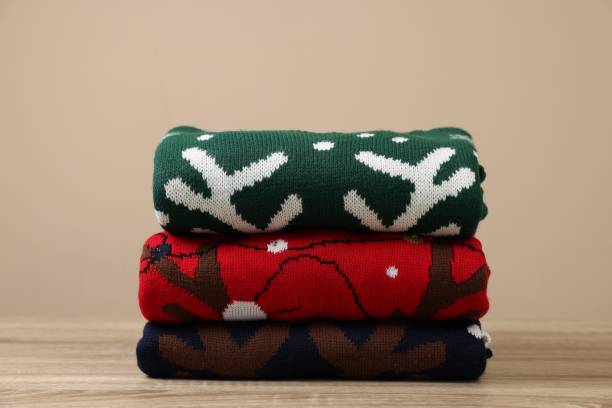 istock Stack of different Christmas sweaters on wooden table against beige background 1828900221