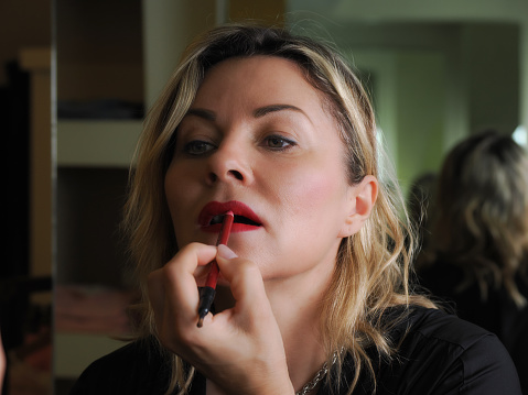 Beautiful beautician putting on lipstick