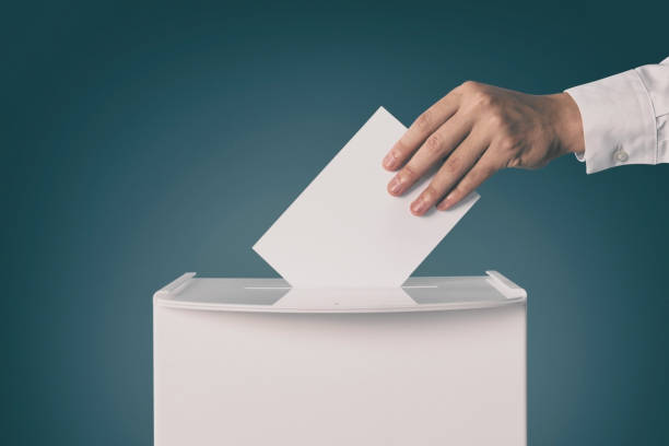 istock Man putting his vote into ballot box on gradient color background, closeup 1828908123