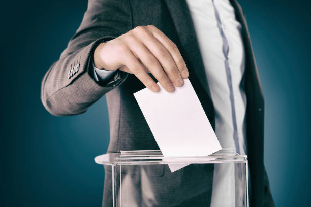 istock Man putting his vote into ballot box on gradient color background, closeup 1828908130