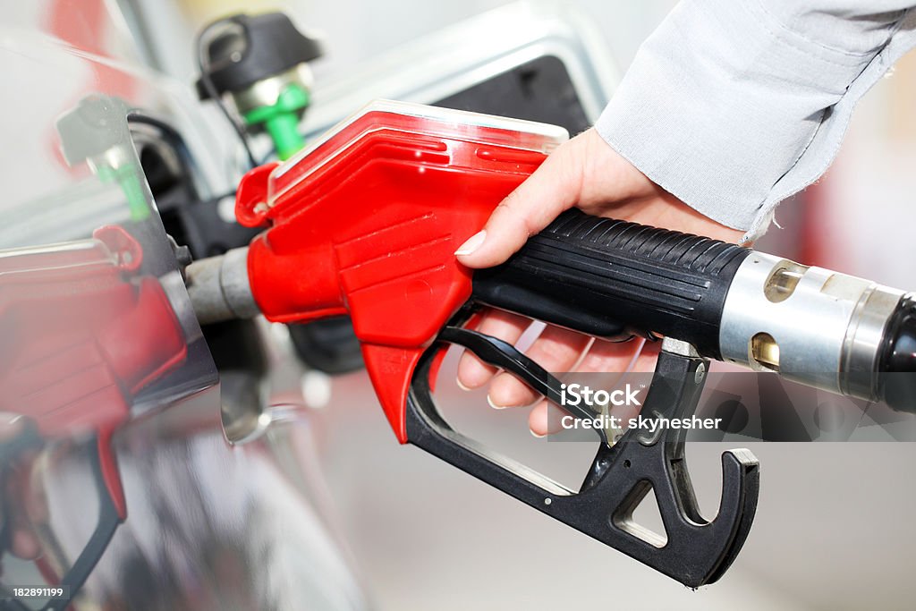 Person refueling a car at gas station. Body part - human hand in foreground refueling a car at gas station. Diesel Fuel Stock Photo