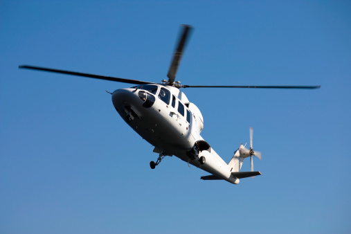 A solid white Sikorsky S76 helicopter carrying executives to a meeting.
