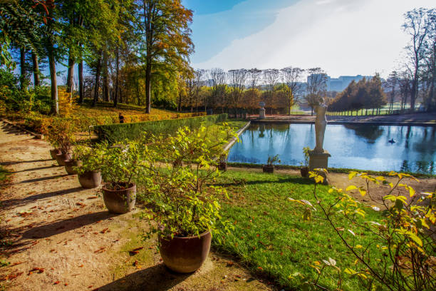Idyllic  autumn  sunny  view on Saint Claude park in Paris .  Old statues and pond . Sportve people runnibg (blurred motion) Seine river in distance. Potted plants