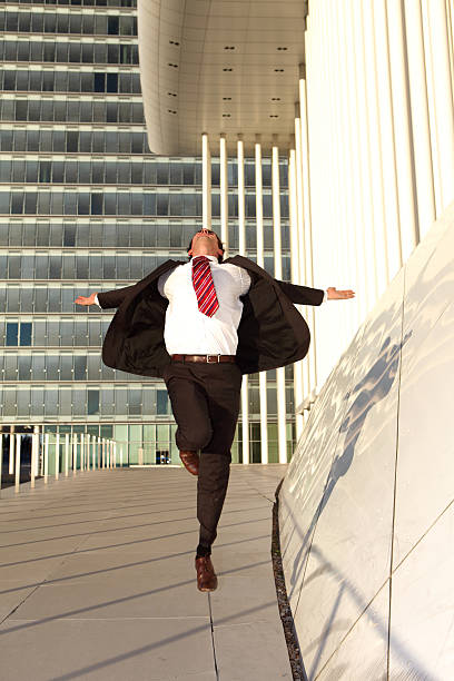 istock Businessman jumping with arms spread out - Modern building background 182891437