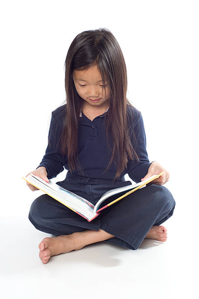 Little Girl Reading "Young asian girl holding book, isolated on white." kid sitting cross legged stock pictures, royalty-free photos & images