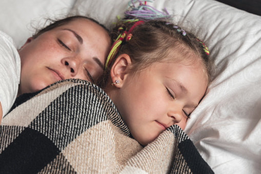 Young mother with daughter sleeping in bed.