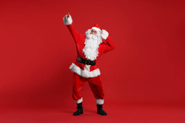 istock Merry Christmas. Santa Claus pointing at something on red background 1828922564