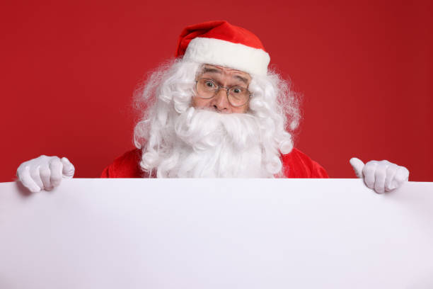 istock Surprised Santa Claus holding blank poster on red background. Space for text 1828922576