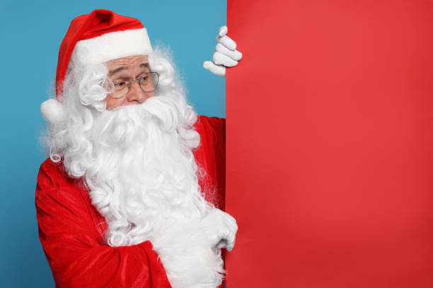istock Santa Claus holding blank red poster on light blue background, space for text 1828924714
