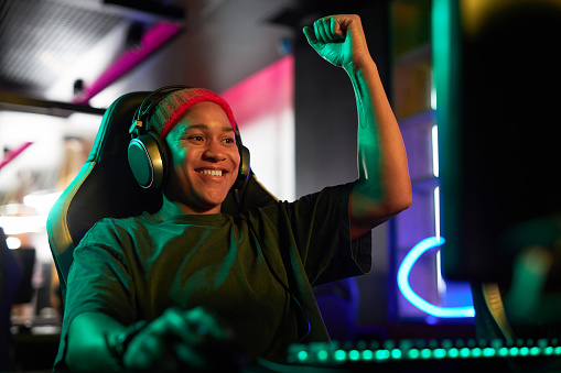 Portrait of smiling African American woman as gamer celebrating victory in neon lighting, copy space