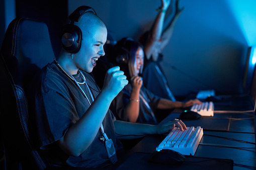 Portrait of happy young woman playing video games and celebrating victory in blue light
