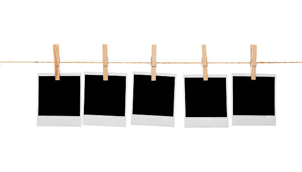 Blank instant photo prints on a washing line Several blank instant photo prints hanging on a rope or washing line. Isolated on white background clothespin stock pictures, royalty-free photos & images