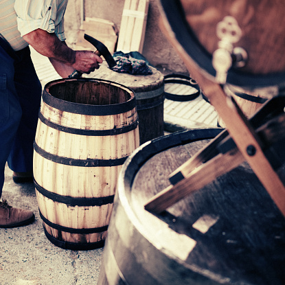 Traditional craftsman making wood barrels. Selective focus in the barrel. Grain.