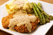 A plate of fried chicken, mashed potatoes and asparagus 