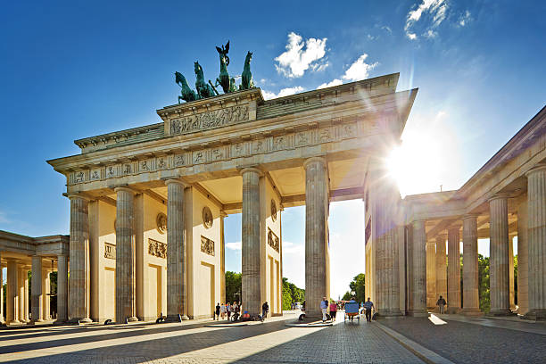 солнце светит через бранденбургские ворота в берлине - berlin germany brandenburg gate germany monument стоковые фото и изображения