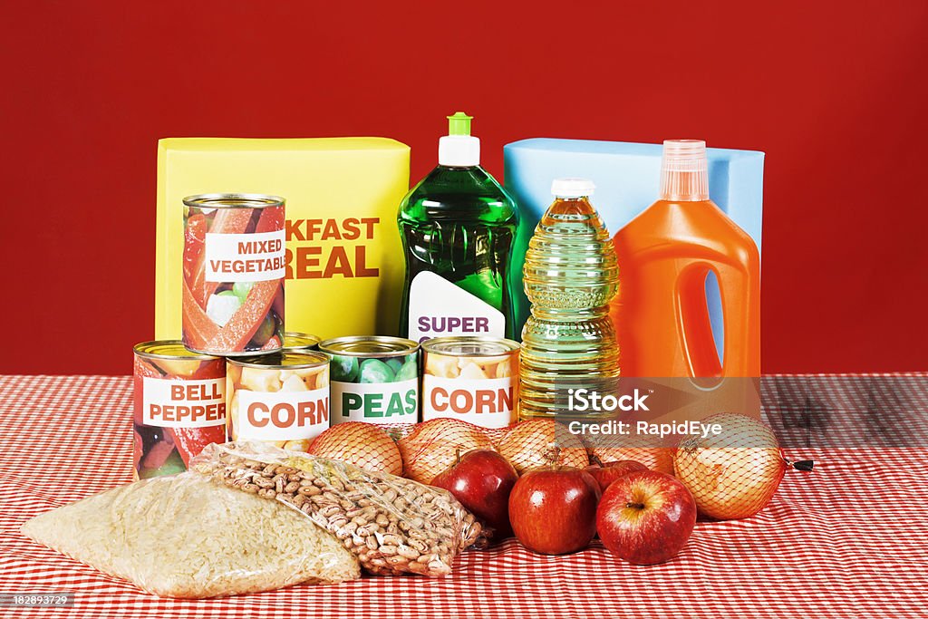 Group of cleaning products and basic foods on kitchen table A selection of cleaning products and basic provisions on a red gingham tablecloth in kitchen. Shot with Canon EOS 1Ds Mark III. Apple - Fruit Stock Photo