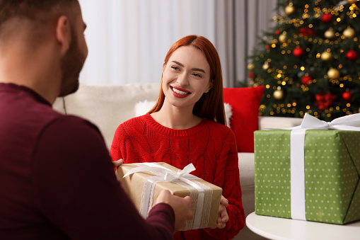 Christmas celebration. Woman and man exchanging gifts at home