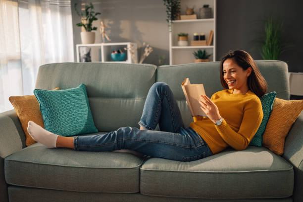 istock A cheerful woman is relaxing at home and reading a book. 1828943158