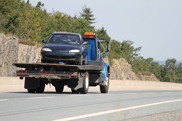 a tow truck with a flatbed carrying an automobile